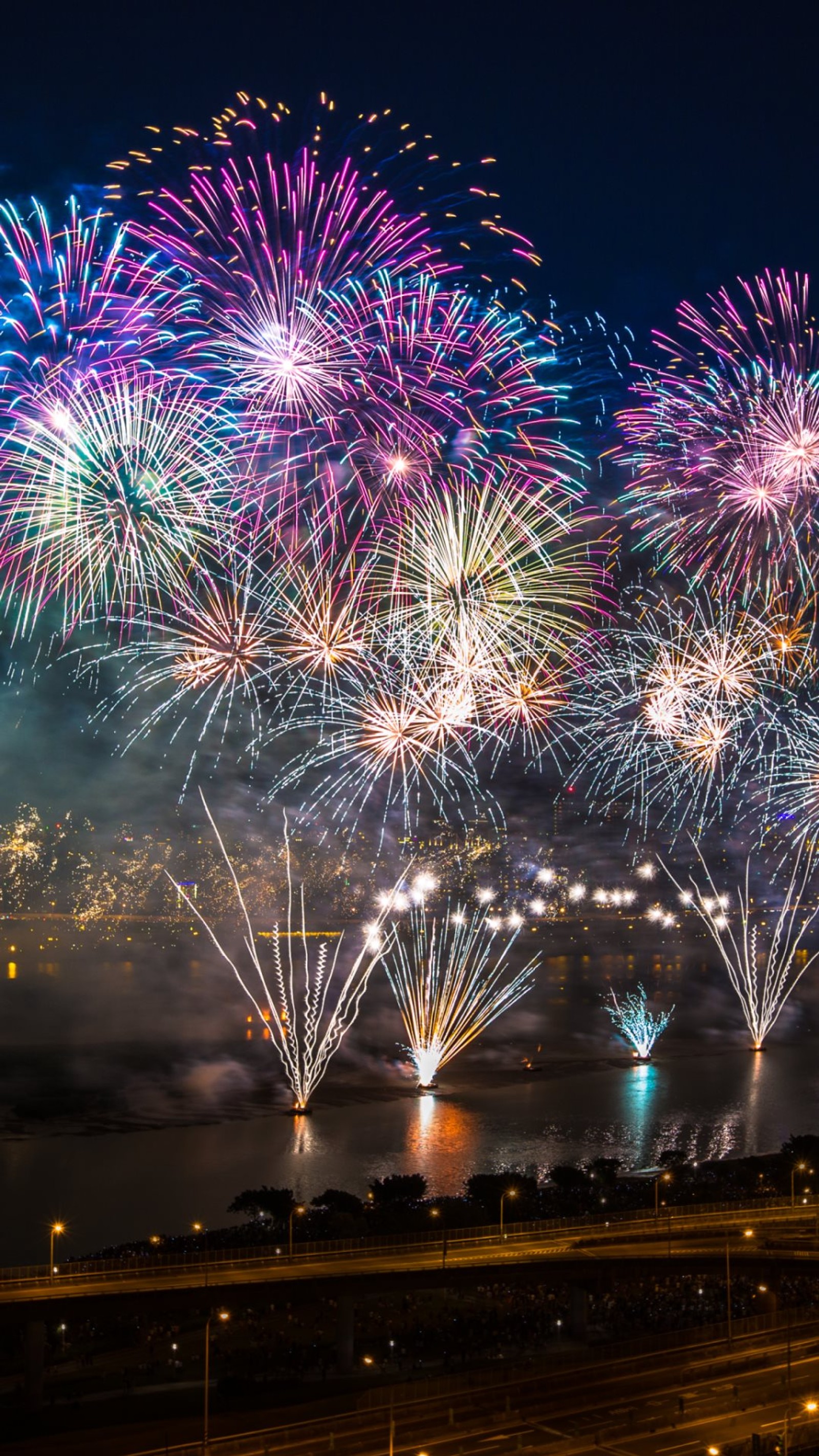 Fireworks are lit up over a city and a river (fireworks, new year)