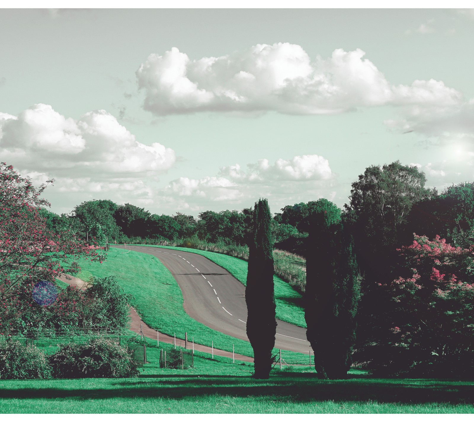 Il y a une image d'une route traversant un champ (nuages, angleterre, england, air frais, paysage)