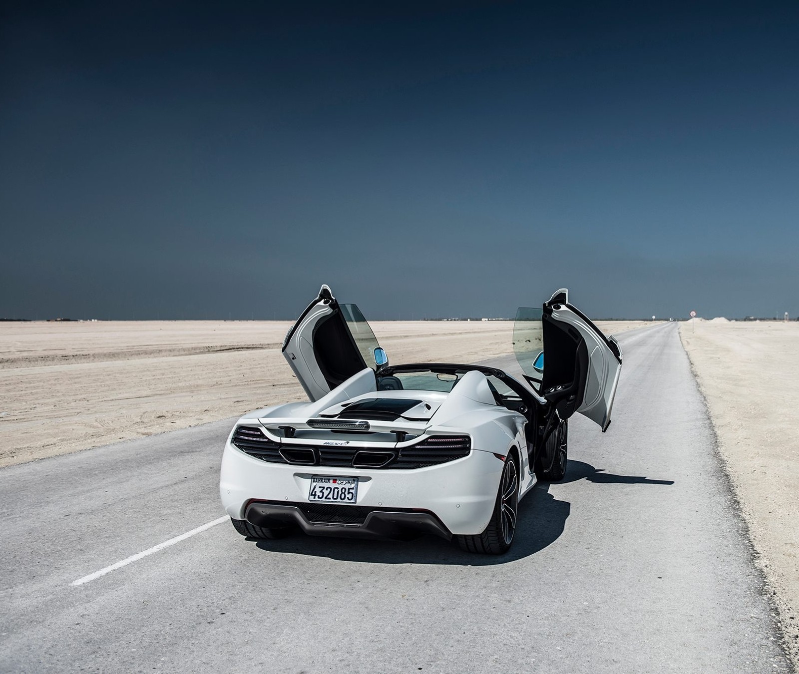 Un gros plan d'une voiture de sport blanche avec les portes ouvertes sur la route (voiture, nouveau, race, vitesse)