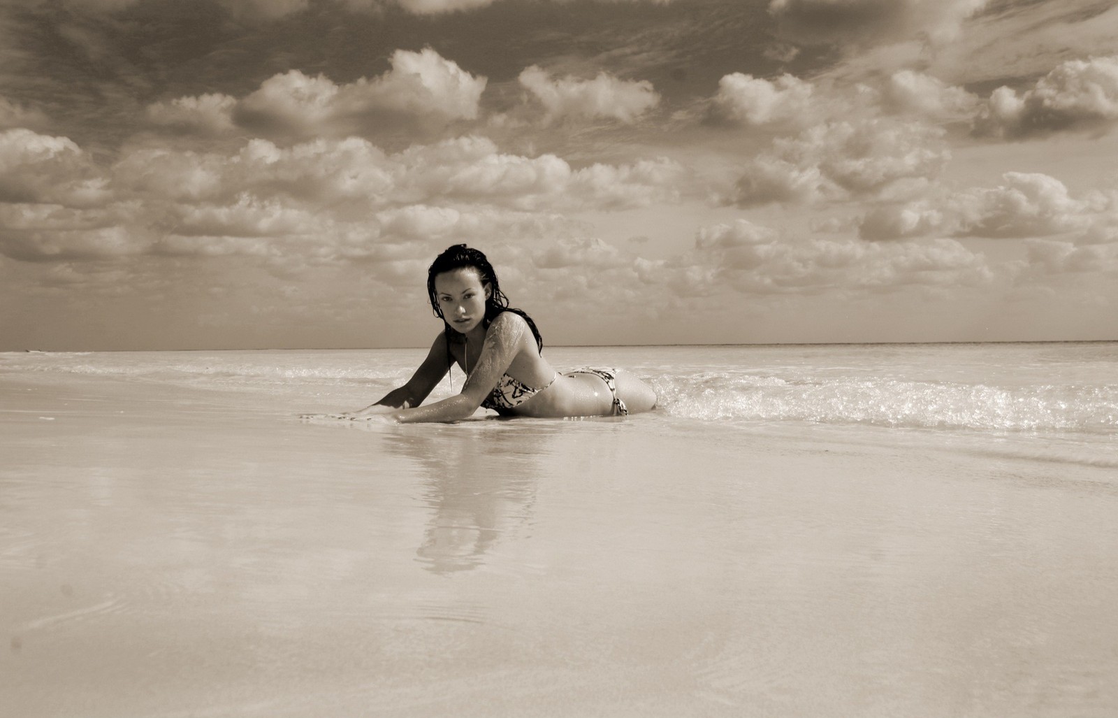 Eine frau liegt auf einem surfbrett am strand (meer, urlaub, welle, ozean, wasser)