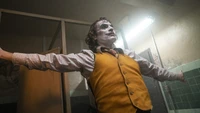 Joaquin Phoenix as the Joker in a pivotal moment of transformation, embracing chaos in a dimly lit setting.