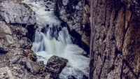 Winterwasserfall, der über einen felsigen Bach fließt