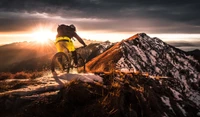 Mountainbiker fährt einen schneebedeckten Grat bei Sonnenaufgang hinunter