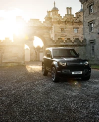 Land Rover Defender 90 V8 Karpaten Edition vor einem historischen Schloss bei Sonnenuntergang.