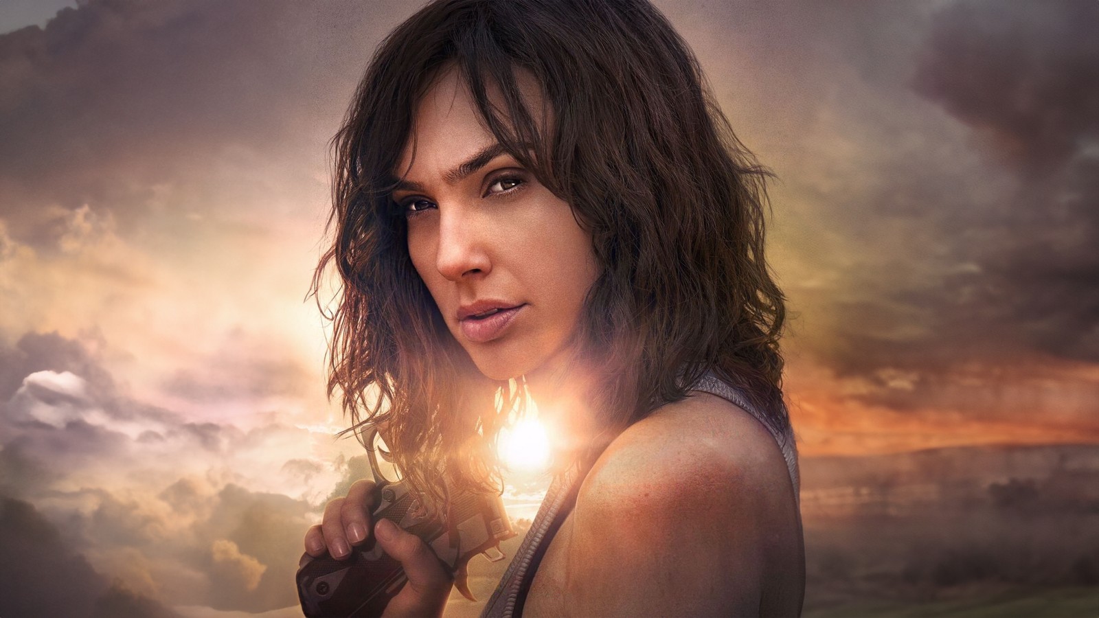 A woman with a gun in her hand standing in front of a sunset (heart of stone, gal gadot, 2023 movies, 5k, movies)