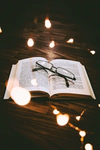 Glasses Resting on an Open Book Surrounded by Soft Lights