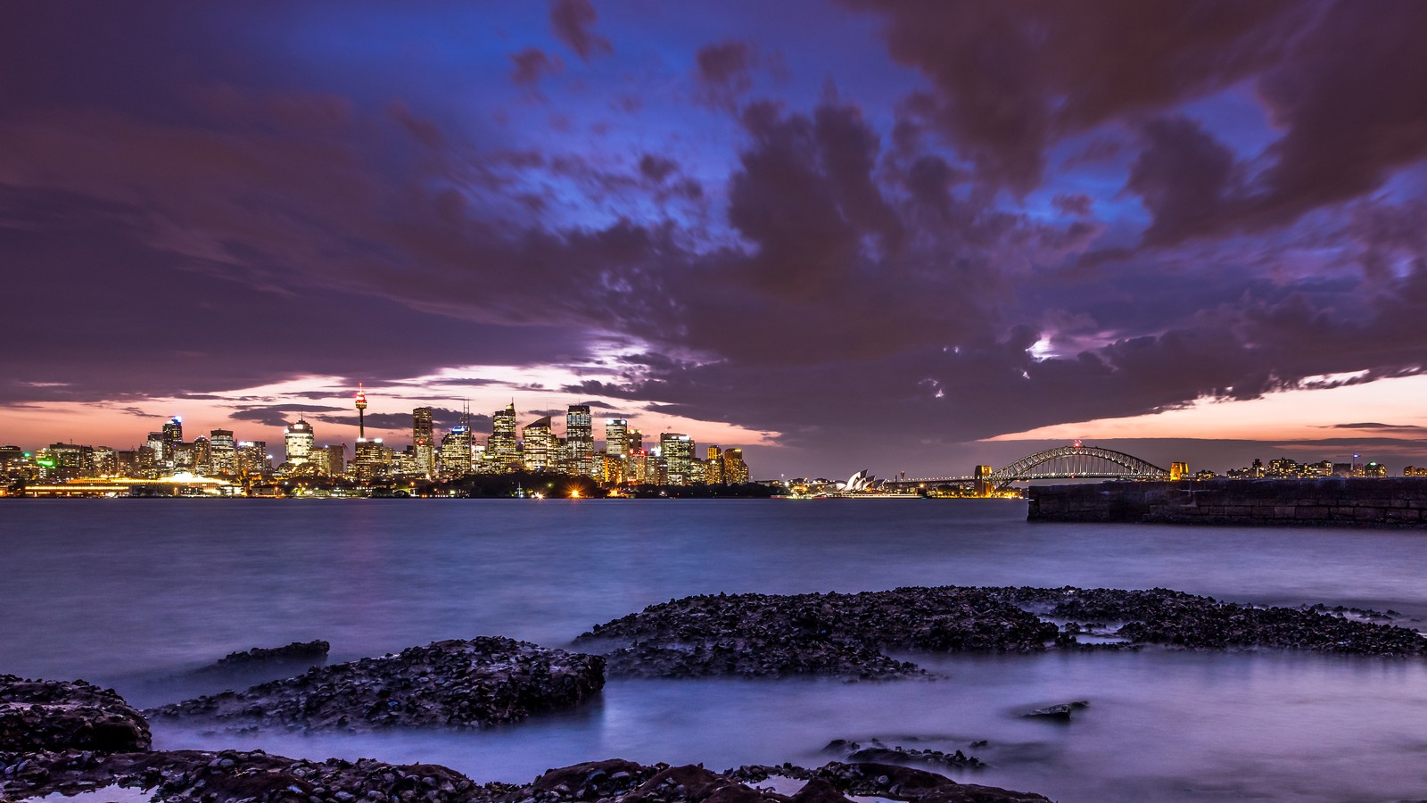 Blick auf die skyline einer stadt vom wasser aus bei sonnenuntergang (sydney, stadtbild, australien, dämmerung, stadtlichter)