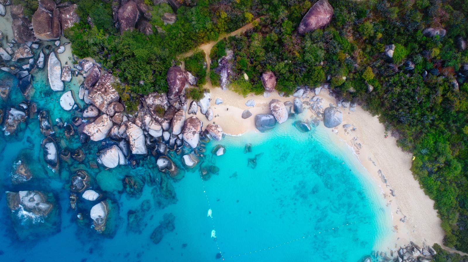 Aerial view of a beach with a lot of rocks and water (sea shore, rocks, blue ocean, aerial view, sand)