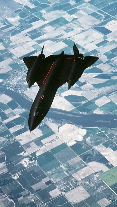 Lockheed SR-71 Blackbird, парящий над лоскутными полями и рекой, демонстрируя свой элегантный дизайн и военную мощь.