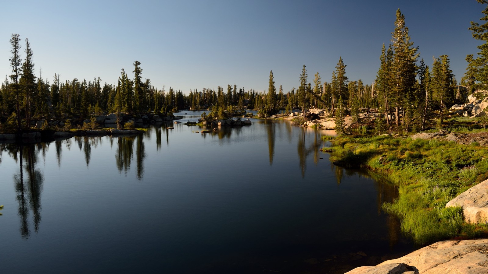 Hay un lago con un pequeño bote rodeado de árboles (lago, naturaleza, árbol, reflexión, cuerpo de agua)