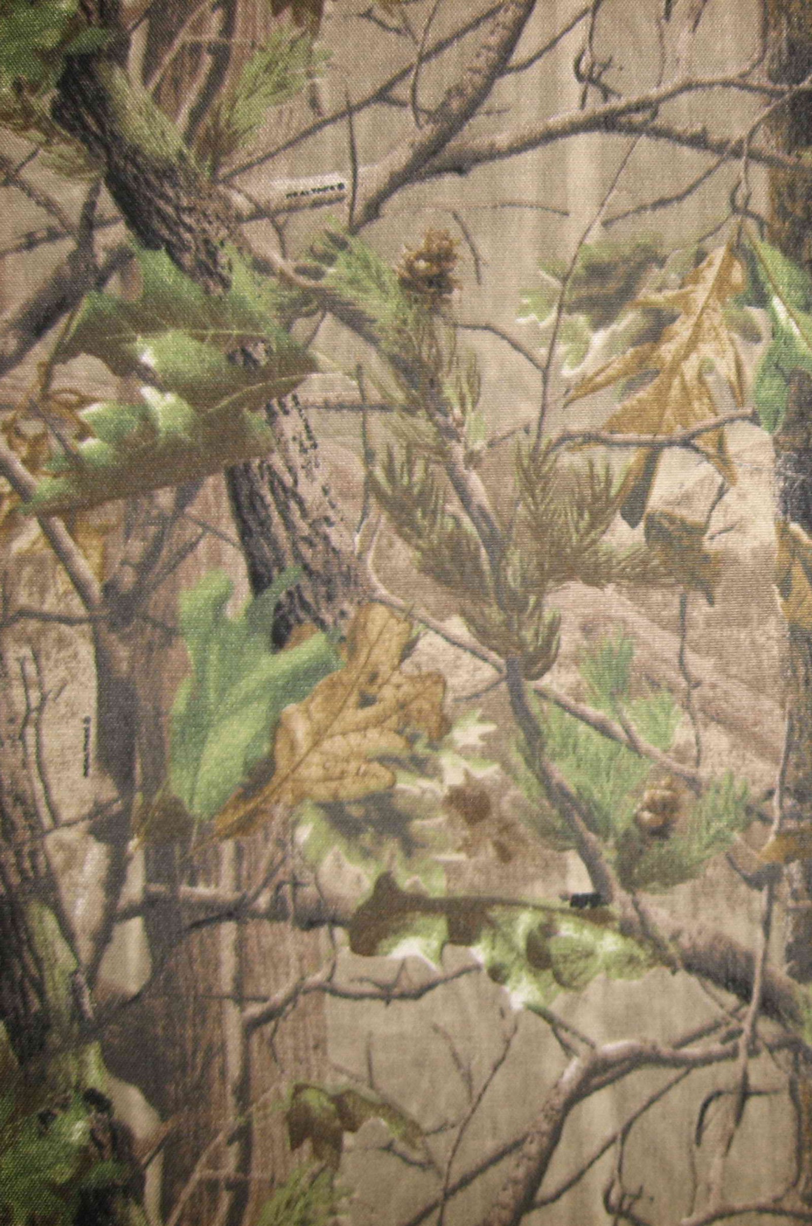 Un gros plan d'un tissu camouflage avec un arbre en arrière-plan (camouflage, chasse, extérieur, realtree)