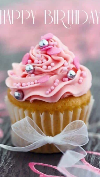 Delicioso cupcake de aniversário coberto com cobertura rosa e confeitos decorativos.