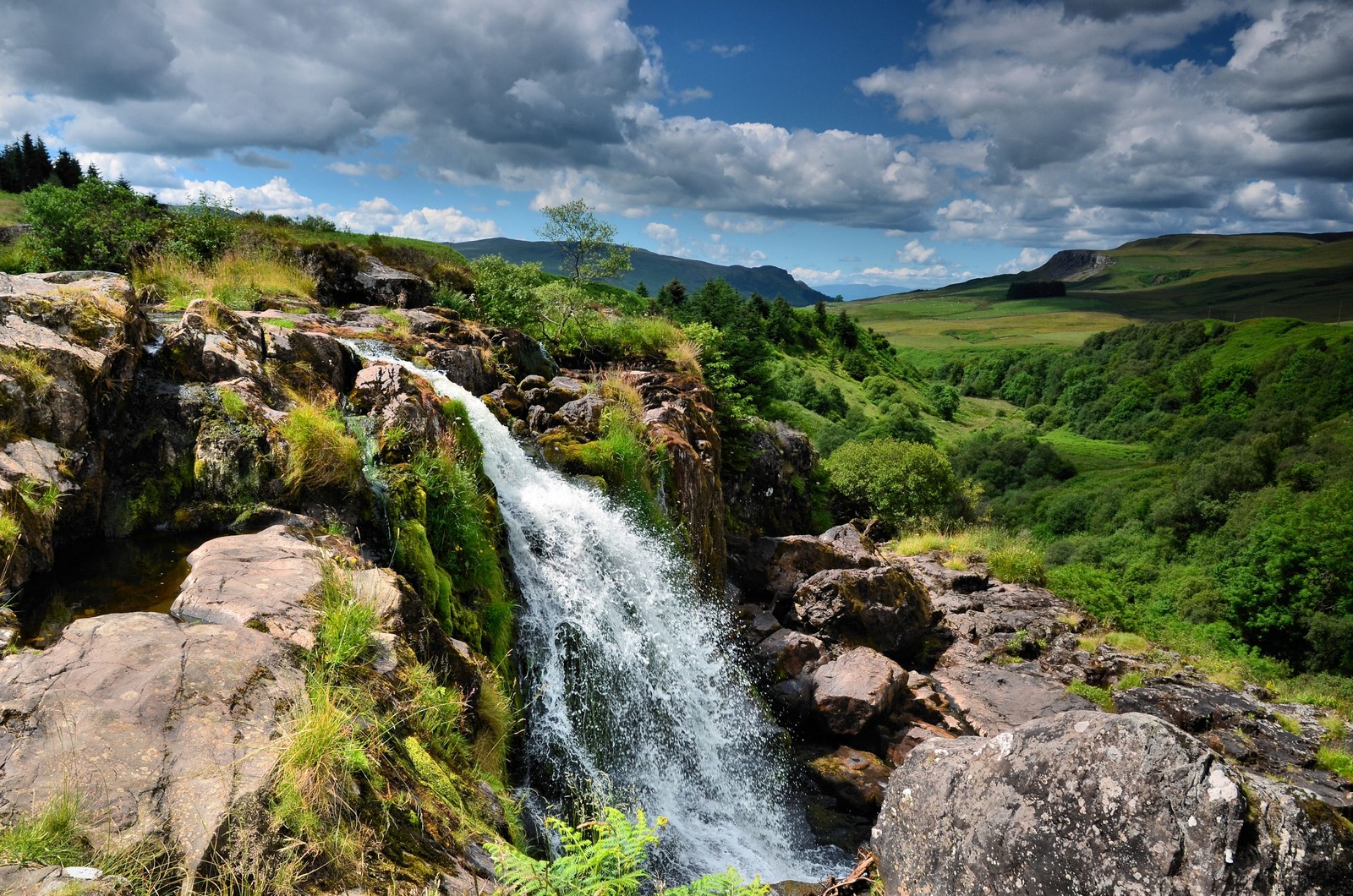 Una vista de una cascada que fluye por un acantilado rocoso en las montañas (naturaleza, cascada, cauce, reserva natural, recursos hídricos)