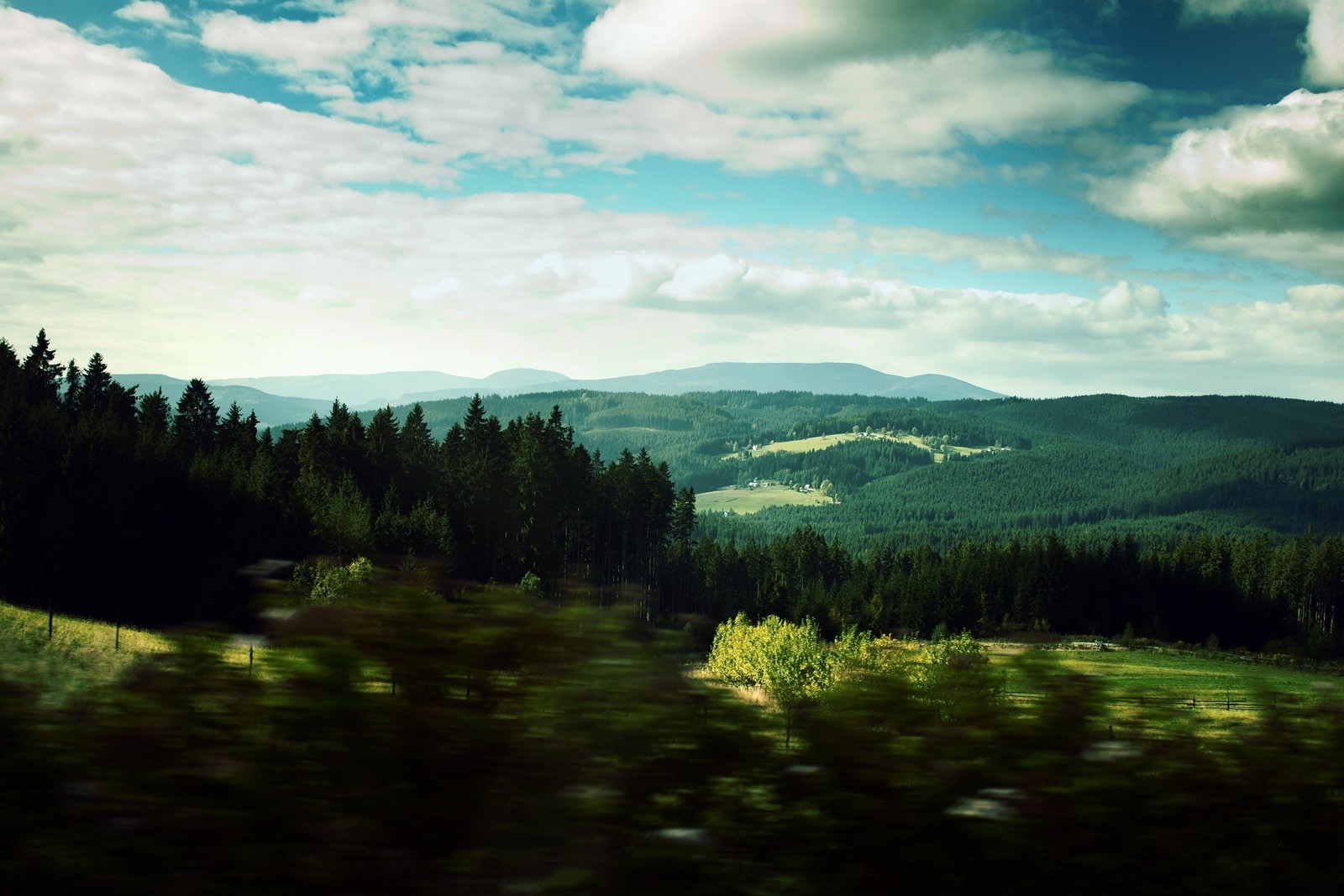 Arafed view of a mountain range with a forest and a field (landscape, nature, green, highland, mountainous landforms)