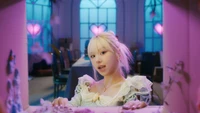 Chaeyoung von TWICE in einer verspielten, pastellfarbenen Umgebung, die eine traumhafte Atmosphäre mit Herzmotiven und sanfter Beleuchtung hervorruft.