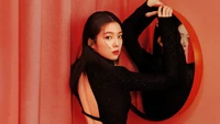 Irene from Red Velvet poses elegantly against a vibrant red backdrop, showcasing her striking profile and a captivating mirror reflection.