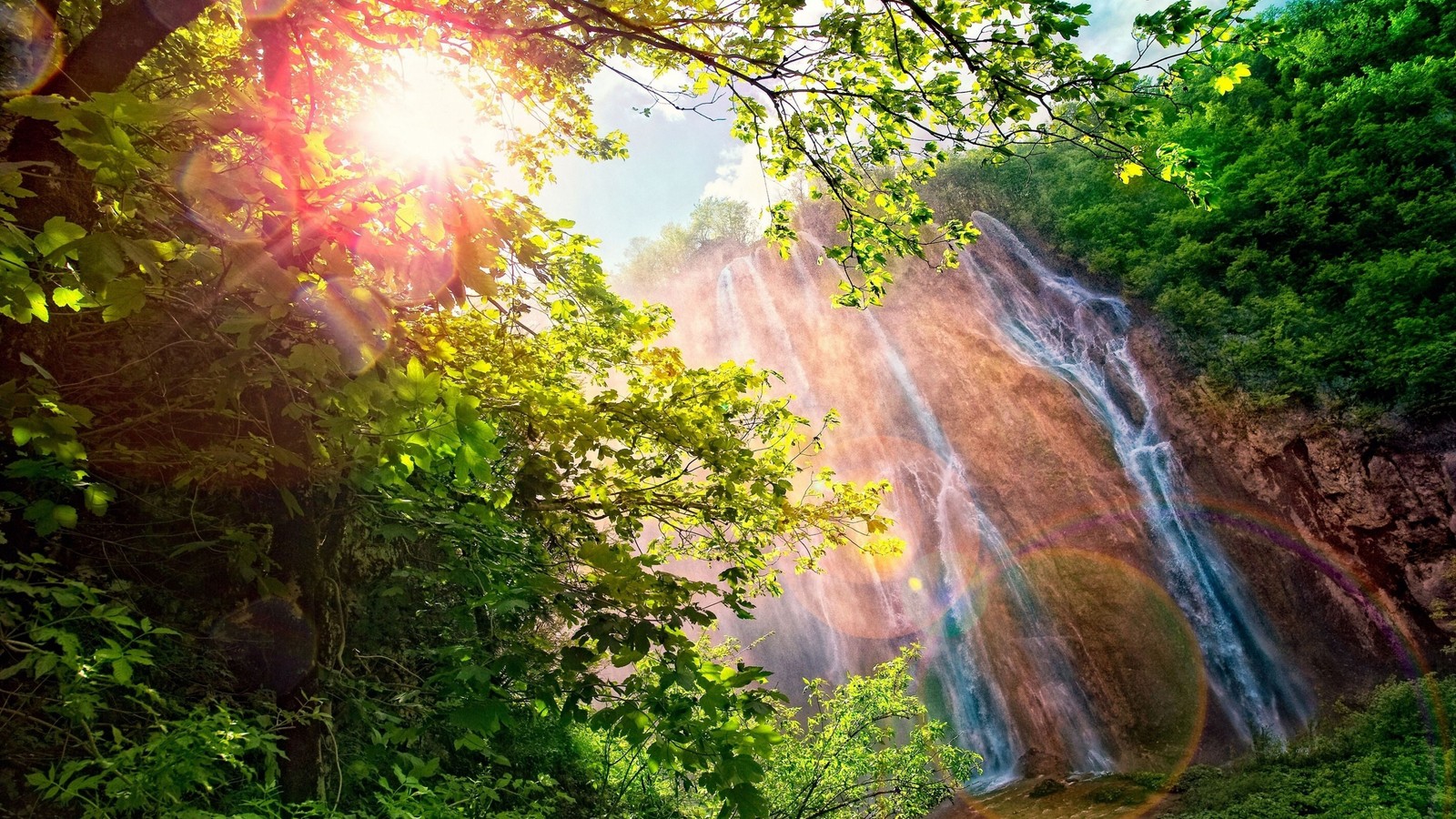 A waterfall in the jungle with sun shining through the trees (waterfall, nature, vegetation, nature reserve, sunlight)