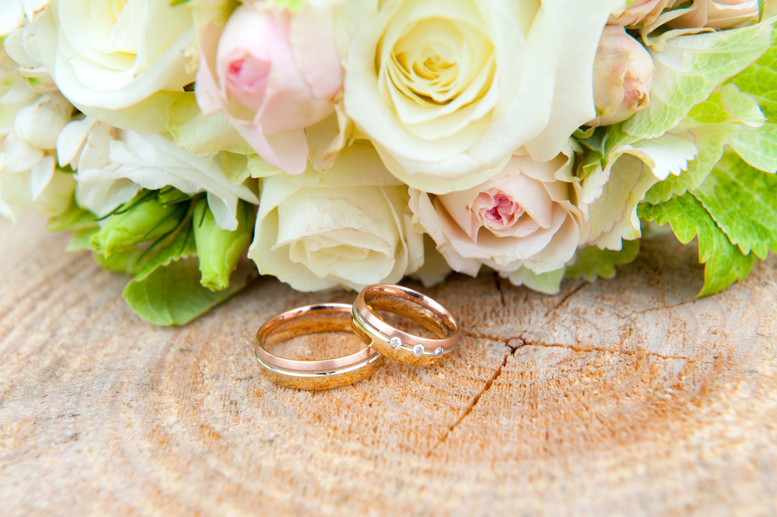 A close up of two wedding rings on a wooden table (wedding anniversary, wedding, anniversary, flower bouquet, bouquet)