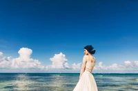 Bonheur nuptial au bord de la mer des Caraïbes : Une mariée en robe blanche sous un ciel bleu