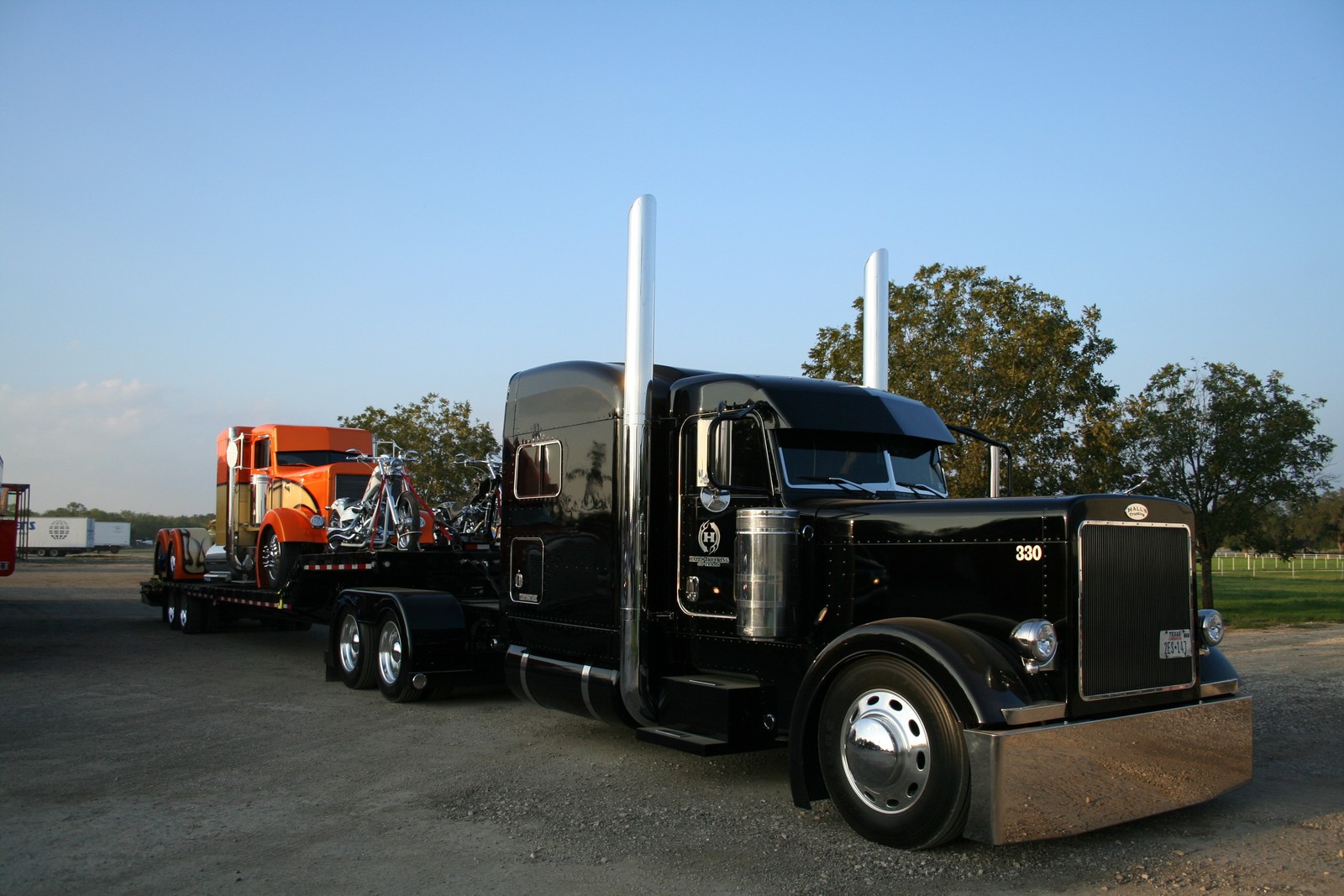 There is a black semi truck with a flat bed trailer (peterbilt, truck, transport, trailer truck, car)