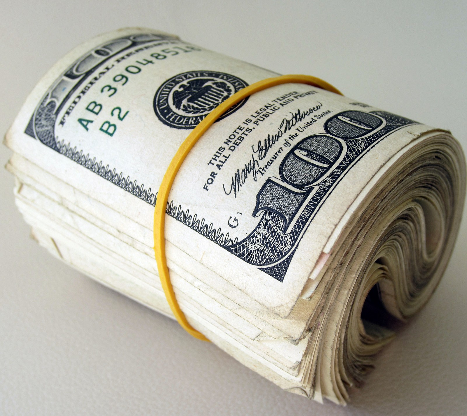 A close up of a roll of money with a yellow string (bills, bling, cash, dollars, money)