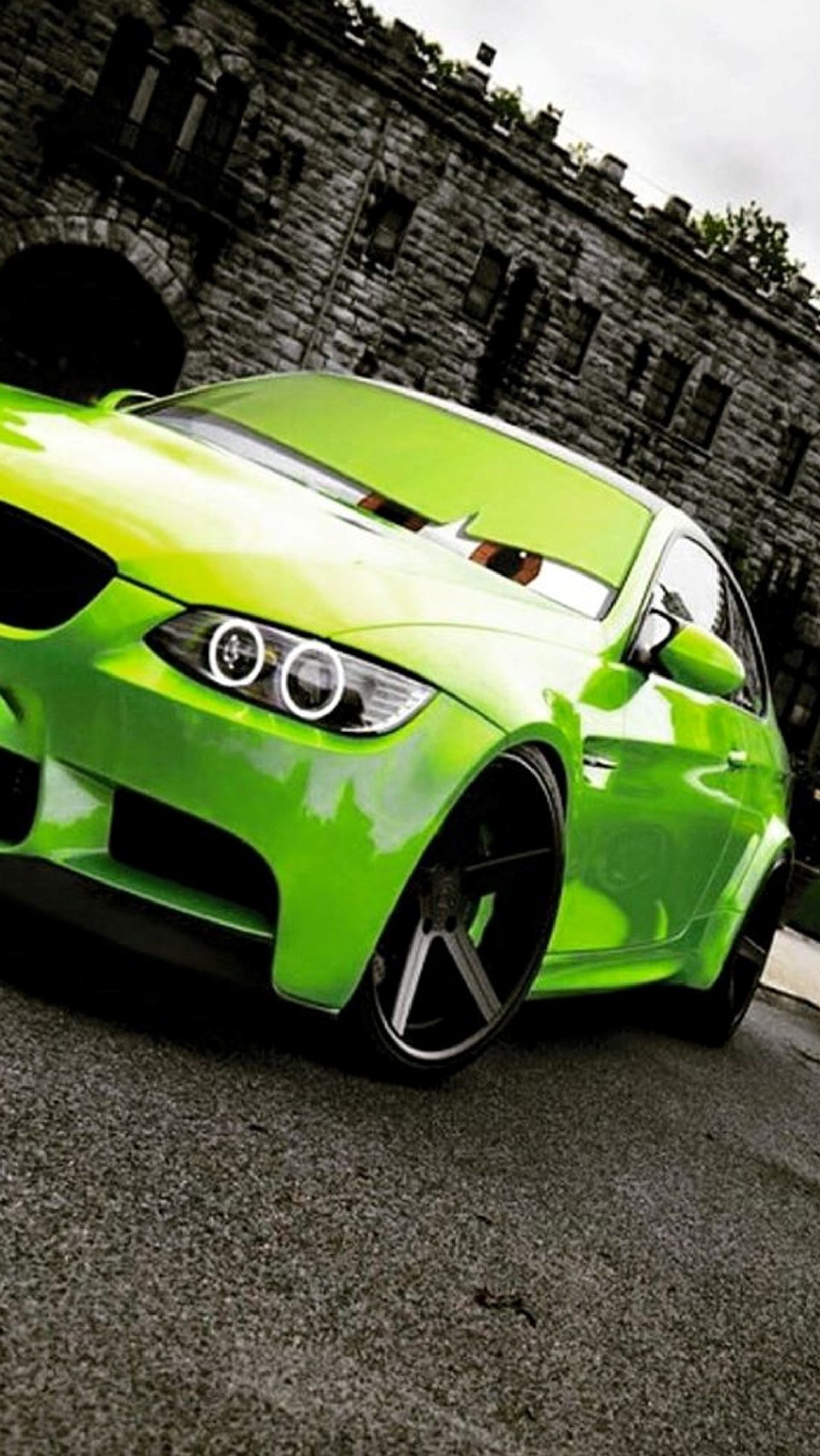 A close up of a green car parked on a street (bmw, car, face, green)