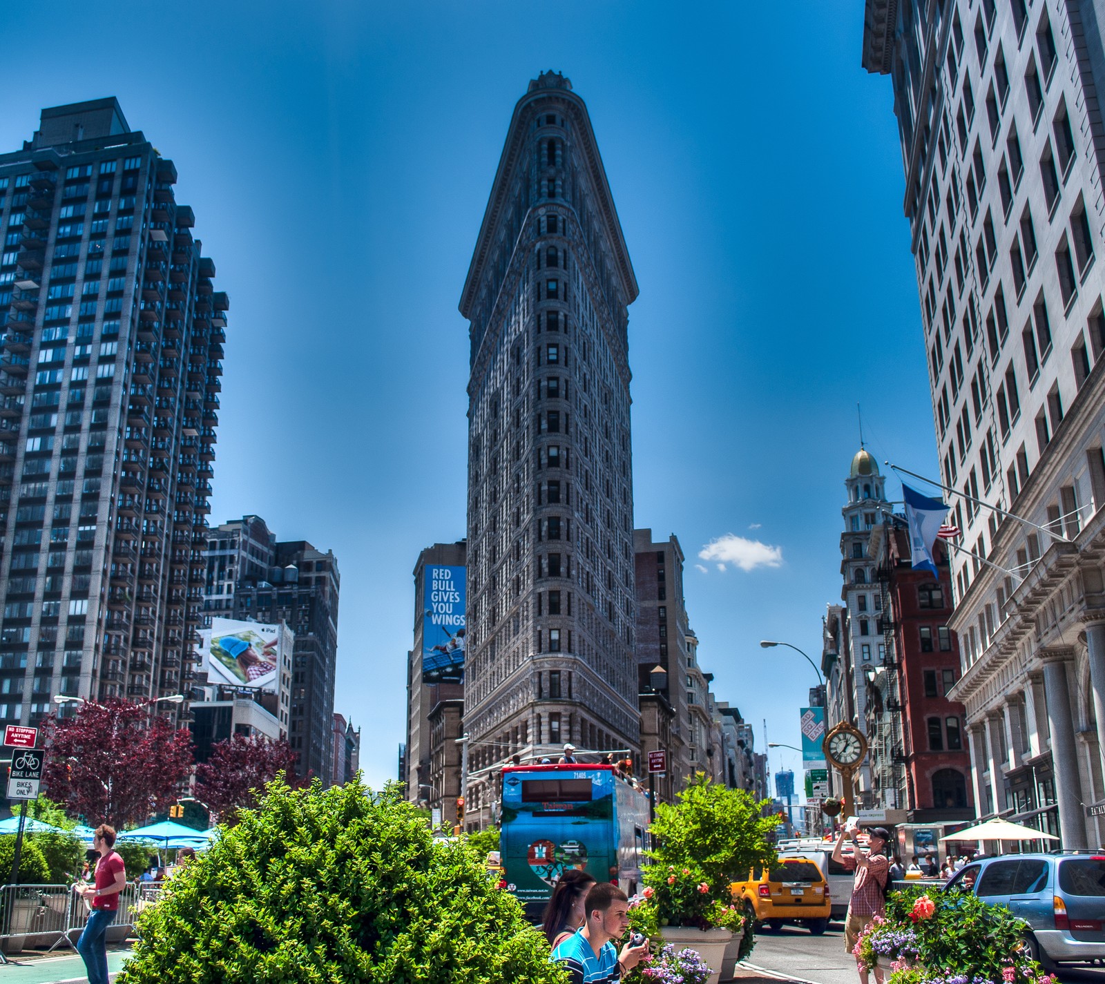 Há uma mulher sentada em um banco no meio de uma cidade (flatiron, manhattan, nova york, new york, nyc)