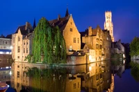 Arquitectura medieval iluminada reflejada en un sereno canal al anochecer