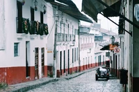 Charming winter alley with picturesque colonial architecture and a vintage Volkswagen Beetle parked amidst cobblestone streets.