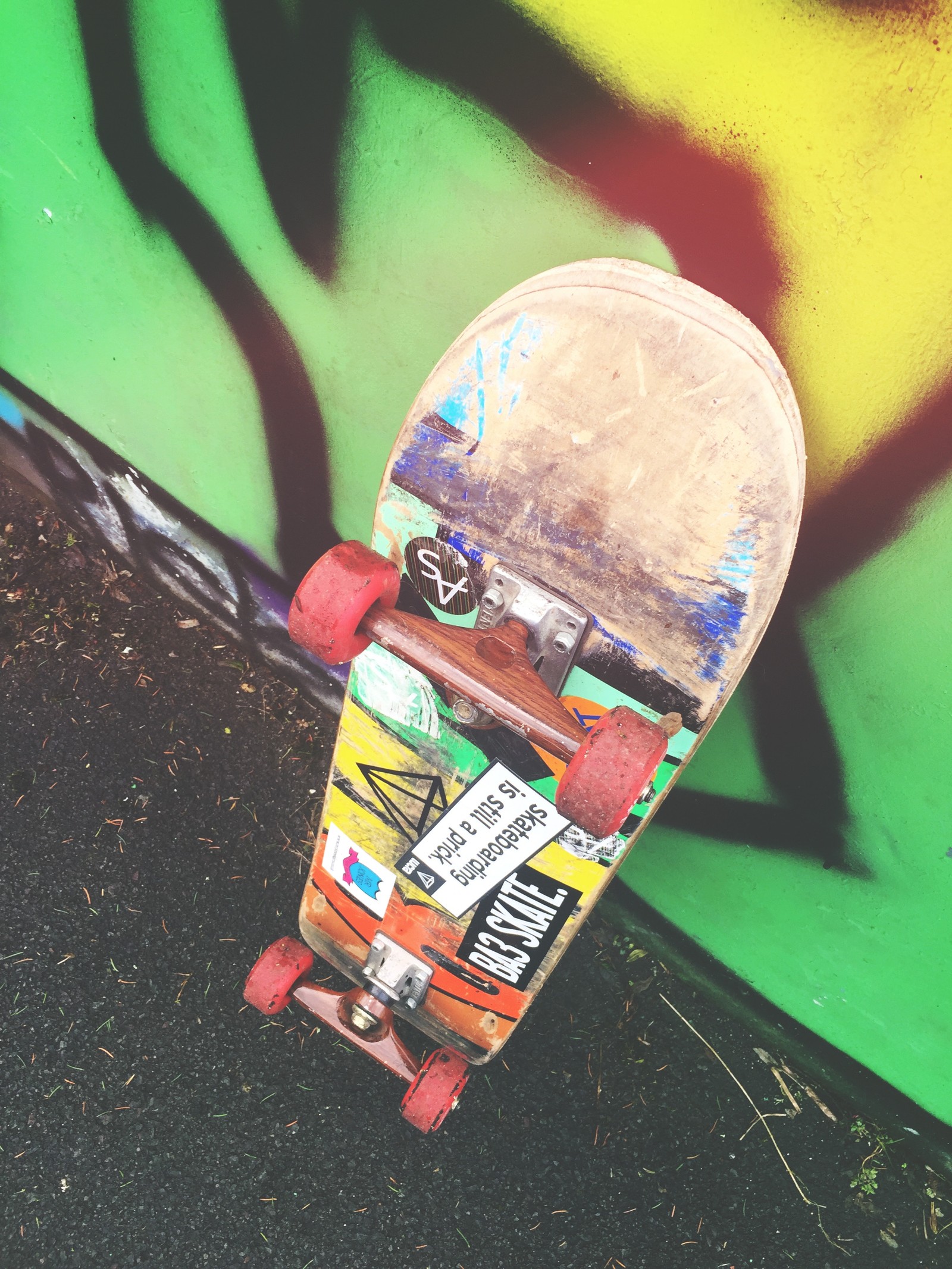 Arafed skateboard with stickers on it leaning against a wall (skateboard, skateboarding, longboard, sports equipment, art)