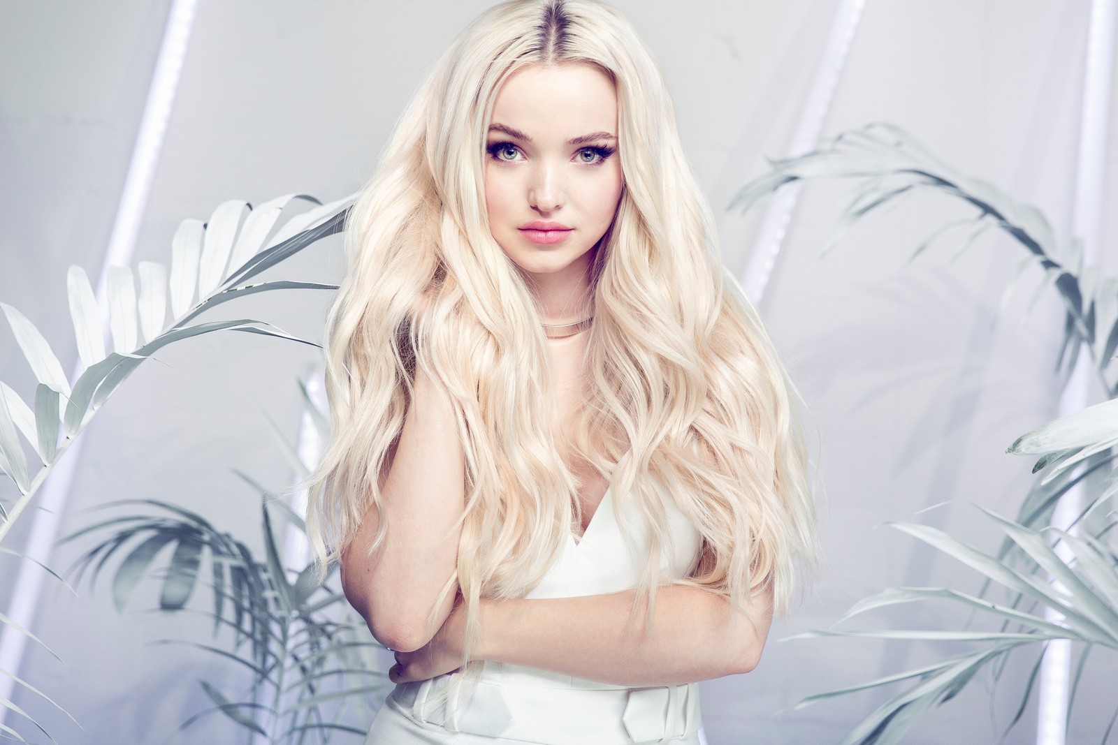 Une femme arabe blonde avec de longs cheveux posant devant une plante (dove cameron, 5k, séance photo, chanteur américain, gens)