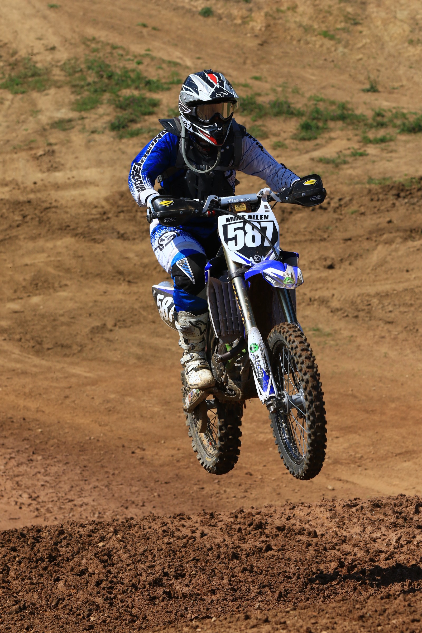 Motociclista en el aire en una pista de tierra. (suelo, motocicleta, todoterreno, motociclismo, motocross estilo libre)