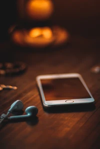 Smartphone and Headphones on a Table with a Warm Glow