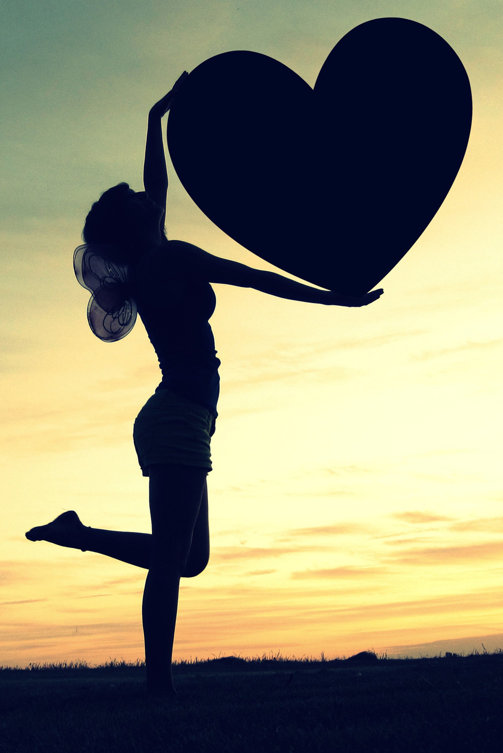 Silhouette d'une femme tenant un objet en forme de cœur dans les airs (cœur, amour, amant, photo)