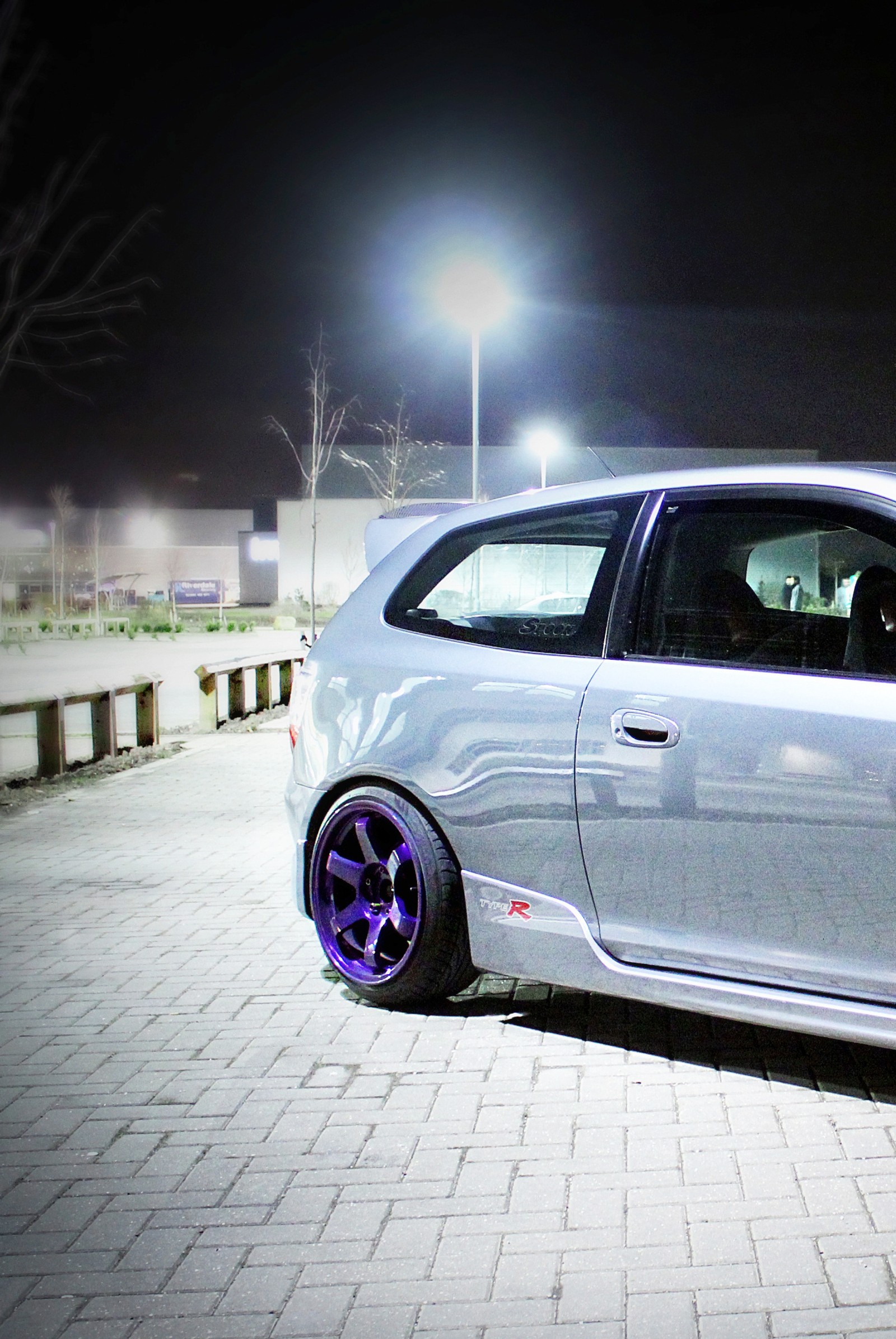 Un coche estacionado en un camino de ladrillos por la noche con un parquímetro (civic, ctr, rejillas, honda, jdm)