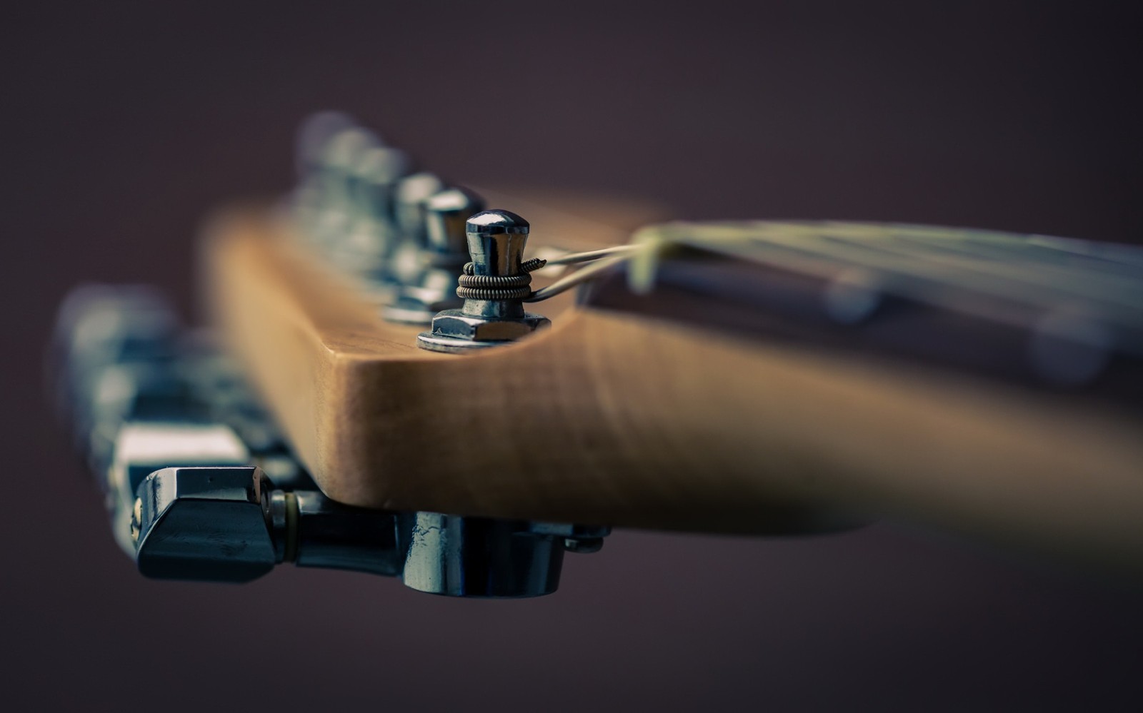 A close up of a guitar neck with a guitar tuner (angle, gun accessory, close up, handheld devices, camera)