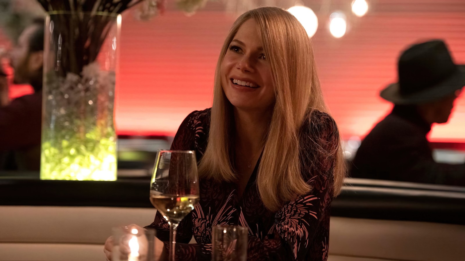 Mulher loira sentada à mesa com um copo de vinho (venom let there be carnage, marvel, filme, 2021, michelle williams)