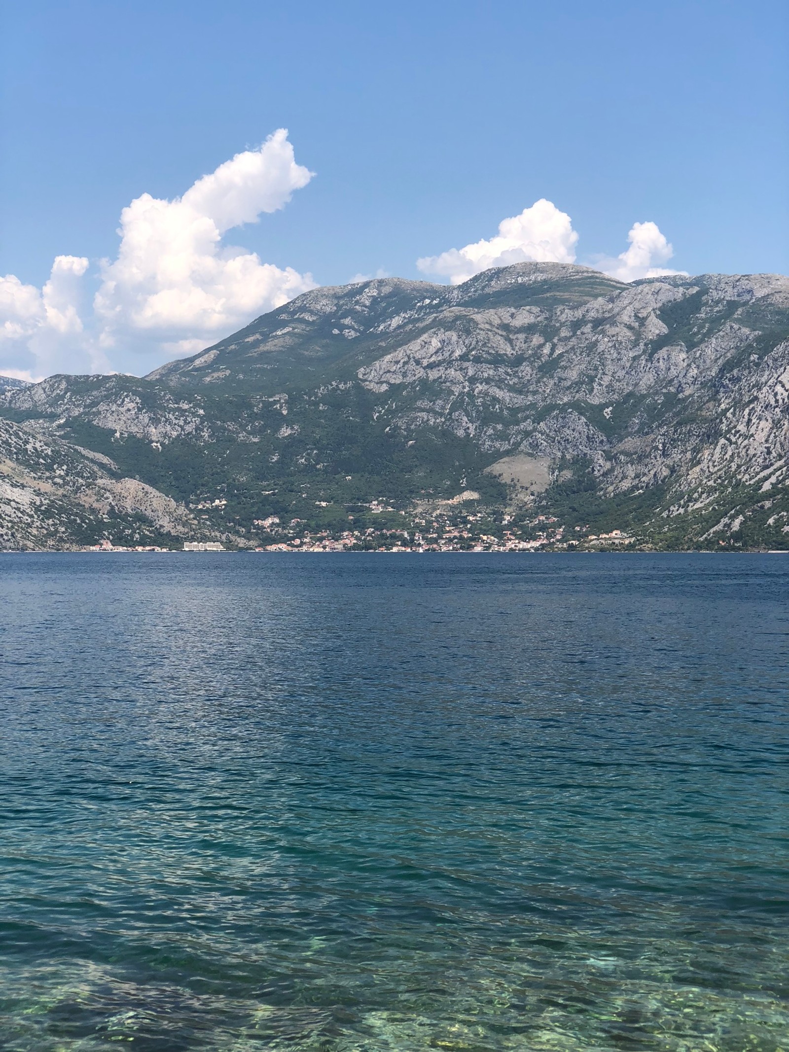 Il y a un bateau flottant dans l'eau près des montagnes (mer, formes montagneuses, nuage, ressources en eau, chaîne de montagnes)