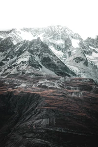 Majestuosa cordillera nevada que se eleva sobre las ásperas tierras altas, mostrando una geología dramática y una naturaleza virgen.