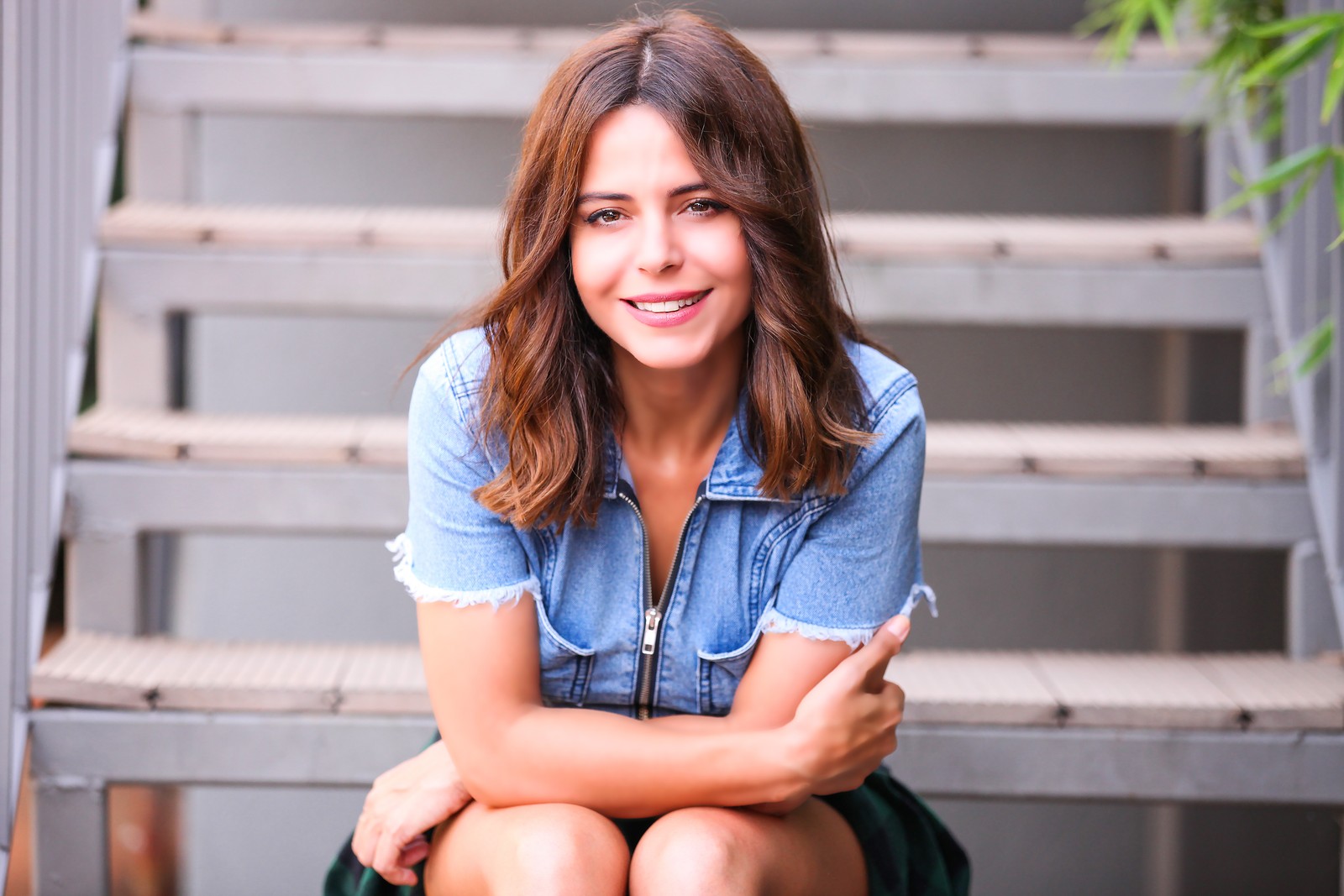 Femme assise sur des marches avec les bras croisés (cheveux, assis, beauté, denim, sourire)