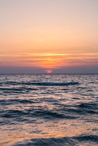 Pôr do sol tranquilo sobre ondas calmas do oceano