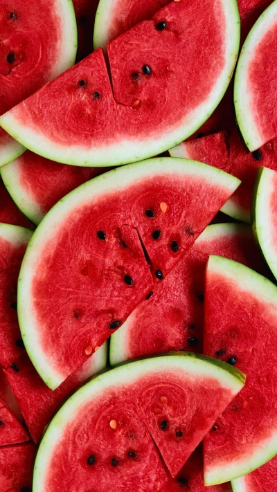 Des morceaux de pastèque fraîchement tranchés disposés de manière artistique, mettant en valeur une chair rouge vibrante et une écorce verte.