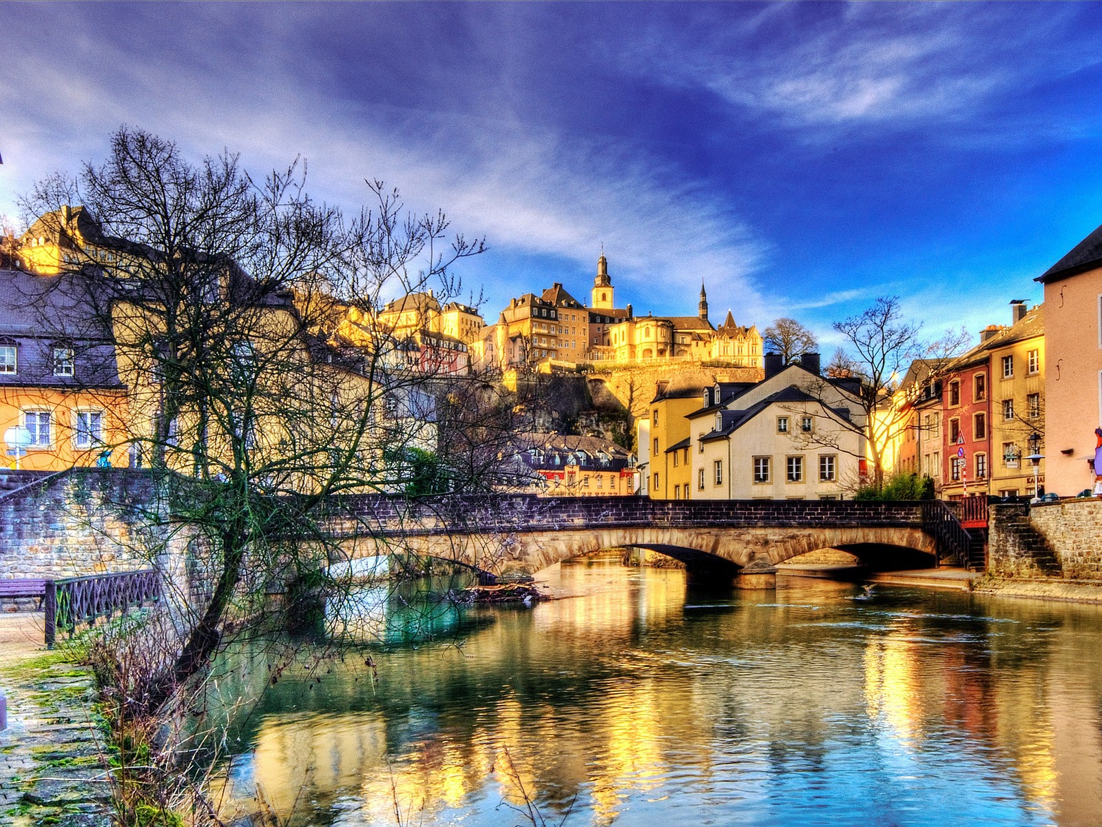 Eine ansicht eines flusses mit einer brücke und gebäuden im hintergrund (reflexion, natur, wasser, wasserstraße, stadt)