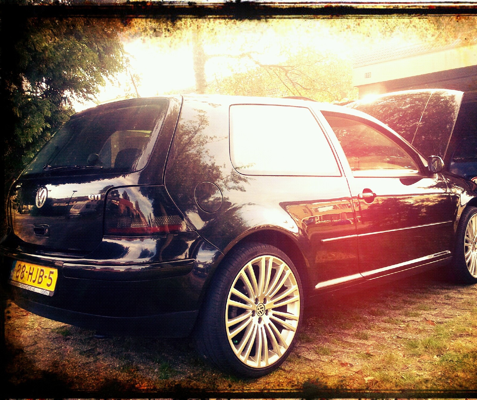 Um carro preto estacionado em frente a uma casa com um cachorro atrás (carros, golfe, gti, volkswagen, vw)