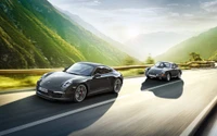 Dynamisches Duo: Klassischer Porsche 930 und moderner 911 auf malerischer Bergstraße