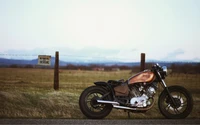 Motocicleta personalizada en un campo abierto con señalización rústica