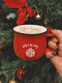 Gemütlicher roter Becher mit heißer Schokolade vor einem festlichen Weihnachtsbaum