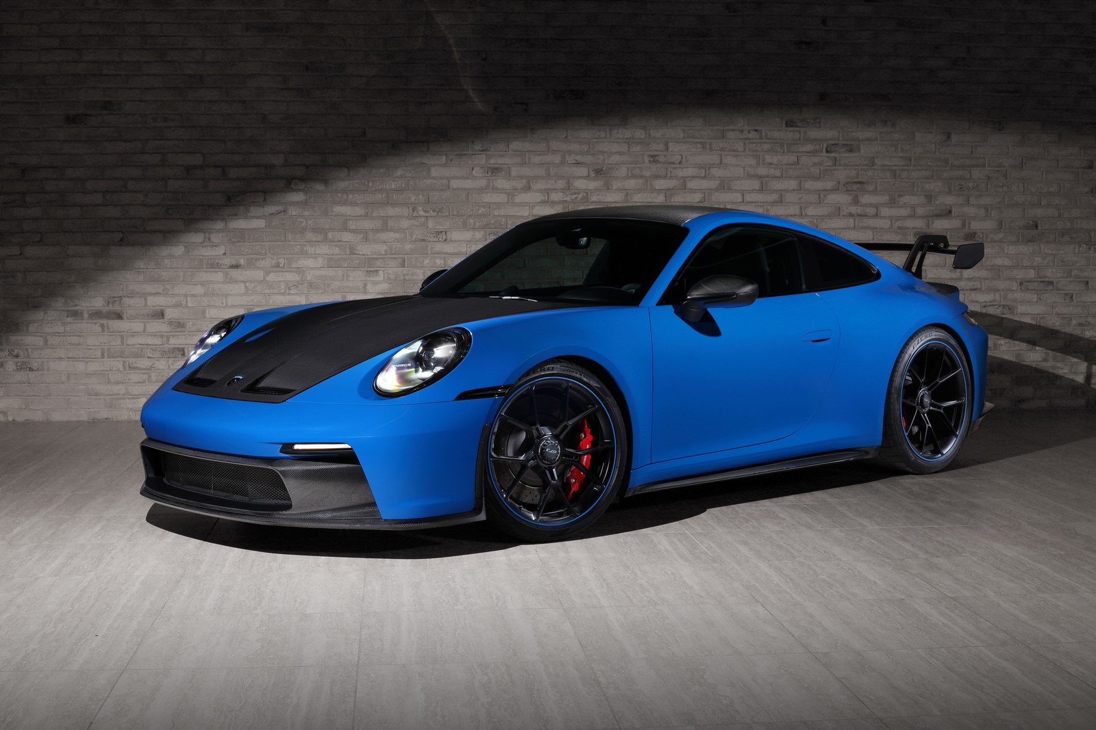 Un porsche gts bleu garé dans une pièce sombre avec un mur en briques (porsche 911 gt3, design topcar, topcar design, 5k, 2023)