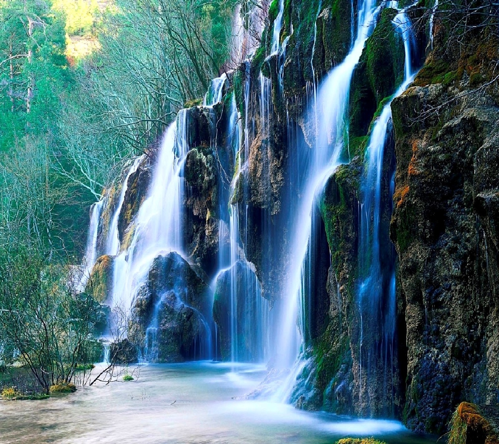 Una cascada en medio de un bosque con algunos árboles (cascada)