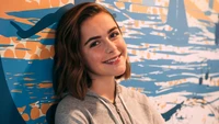 Kiernan Shipka sorrindo contra um mural colorido